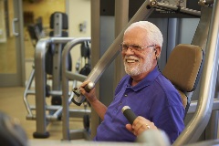 Smiling, older man exercising in a gym.